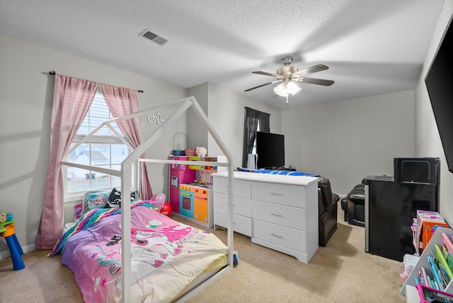 bedroom with a textured ceiling, light carpet, visible vents, and a ceiling fan