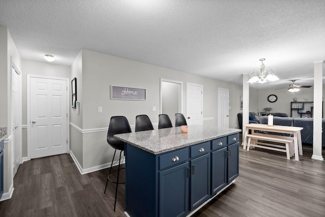 kitchen with a breakfast bar area, a kitchen island, dark wood finished floors, and blue cabinets