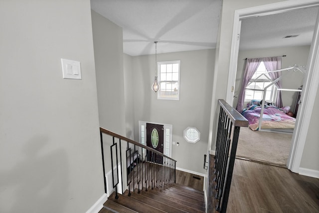 stairway with a wealth of natural light, baseboards, visible vents, and wood finished floors