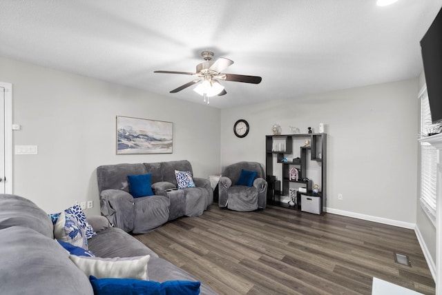 living room featuring baseboards, visible vents, a ceiling fan, dark wood-style floors, and a fireplace