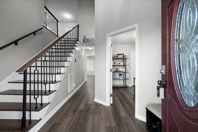 foyer with a towering ceiling, wood finished floors, visible vents, and baseboards