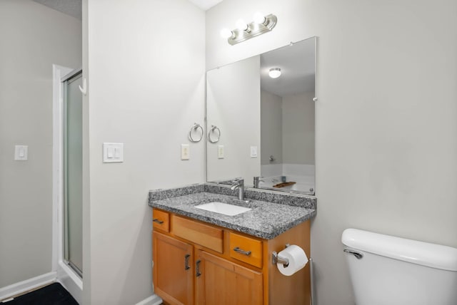 bathroom featuring a stall shower, vanity, toilet, and baseboards