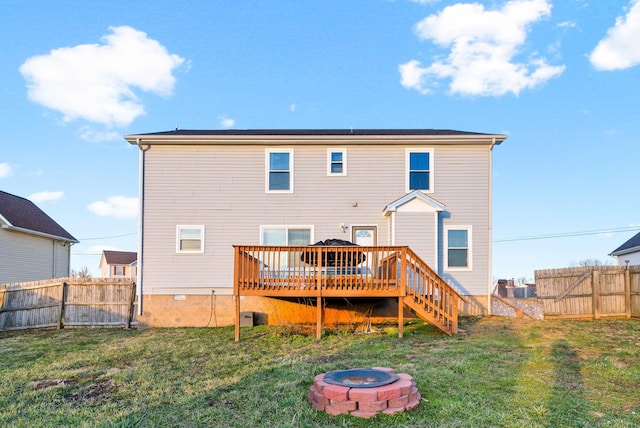 back of house featuring an outdoor fire pit, a lawn, a deck, and fence