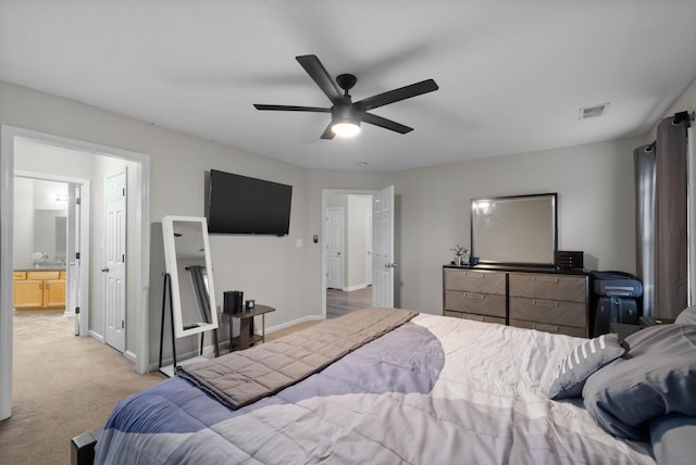 bedroom with ceiling fan, light carpet, visible vents, baseboards, and ensuite bath