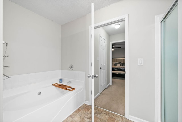 ensuite bathroom with a garden tub, ensuite bath, a textured ceiling, and baseboards