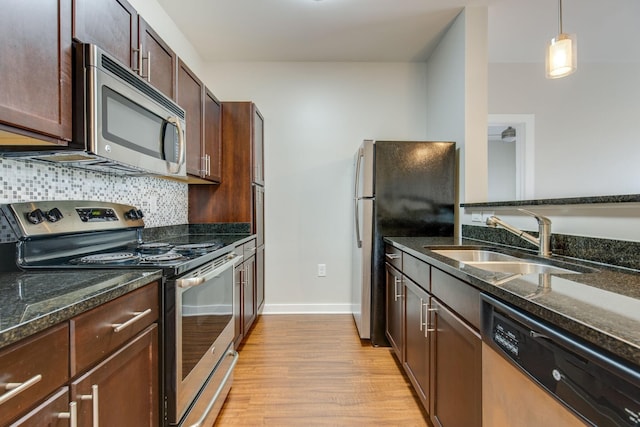 kitchen with backsplash, dark stone counters, stainless steel appliances, and a sink