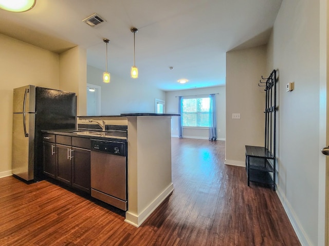 kitchen featuring visible vents, dark countertops, dark wood-type flooring, stainless steel appliances, and a sink