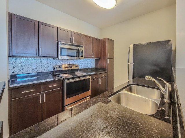 kitchen featuring stainless steel appliances, decorative backsplash, a sink, dark stone countertops, and dark brown cabinets