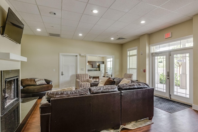 living room featuring a towering ceiling, a premium fireplace, visible vents, and dark wood-style flooring