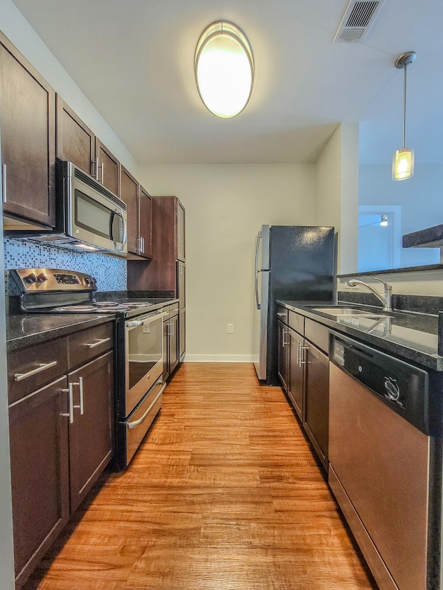 kitchen featuring light wood finished floors, stainless steel appliances, visible vents, a sink, and dark brown cabinets