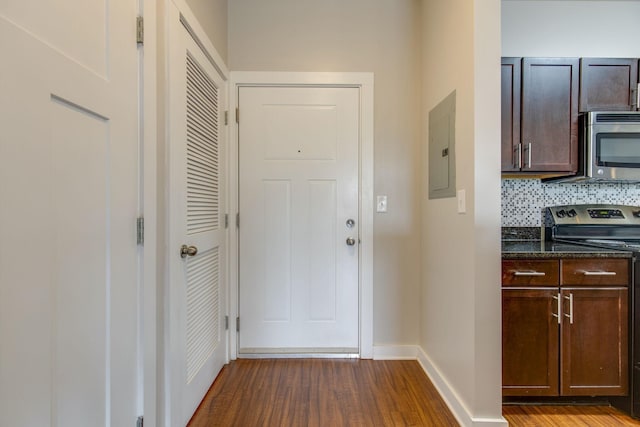 entryway with dark wood-type flooring, electric panel, and baseboards