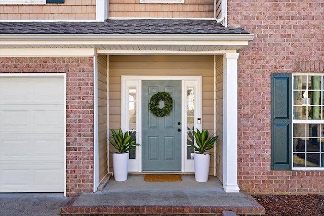 doorway to property with a garage, brick siding, and roof with shingles