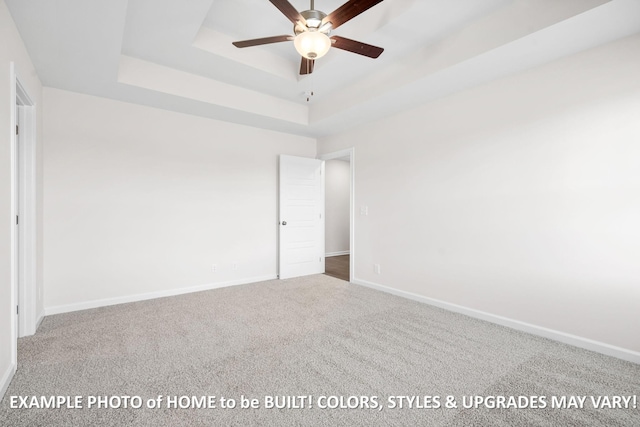 unfurnished bedroom featuring carpet, a raised ceiling, and baseboards