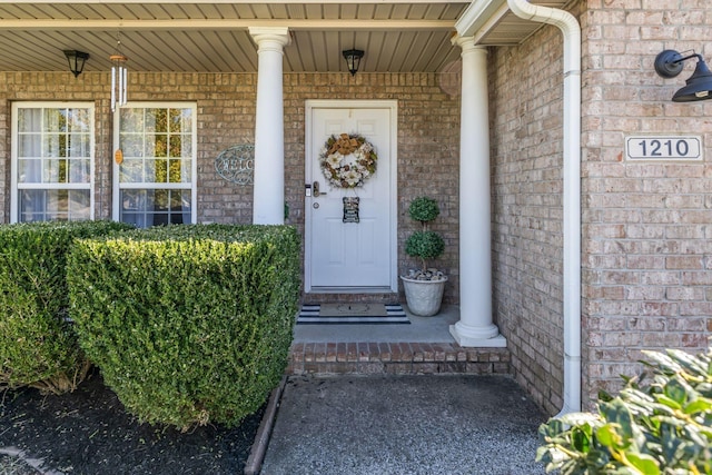 property entrance with covered porch and brick siding