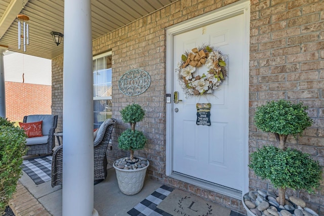 view of exterior entry with covered porch and brick siding