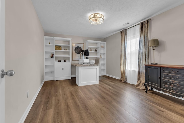 unfurnished office with visible vents, a textured ceiling, baseboards, and dark wood-type flooring