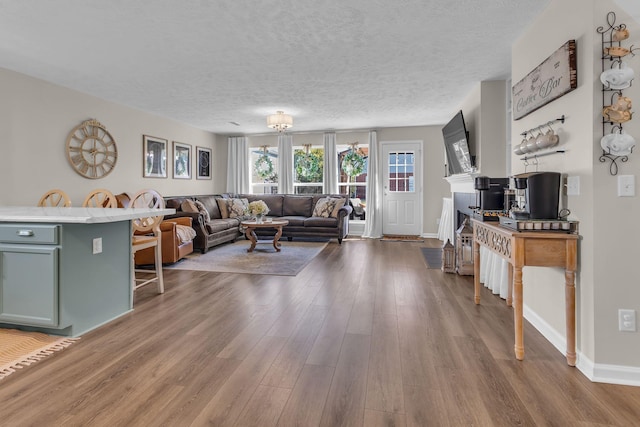 living room with a textured ceiling, wood finished floors, and baseboards