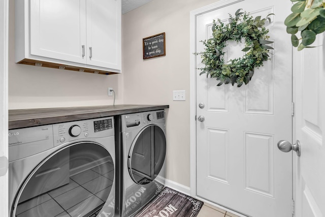 clothes washing area with tile patterned flooring, washing machine and clothes dryer, cabinet space, and baseboards