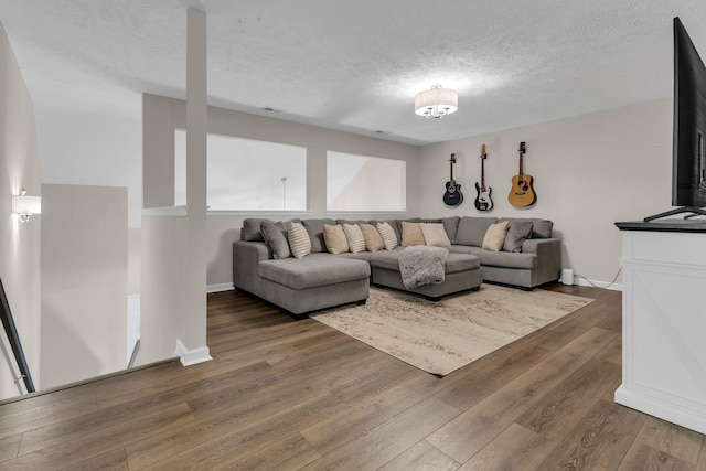 living room featuring a textured ceiling, baseboards, and wood finished floors