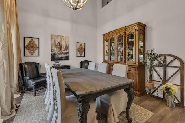 dining space with a chandelier, a towering ceiling, and wood finished floors