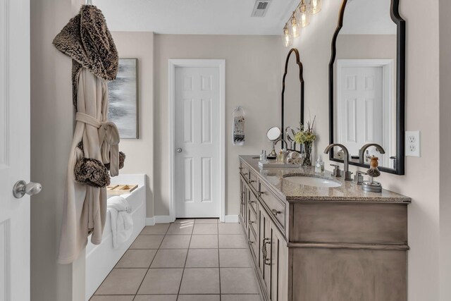 full bathroom featuring double vanity, visible vents, tile patterned floors, a garden tub, and a sink