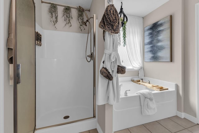 bathroom with a garden tub, a shower stall, baseboards, and tile patterned floors