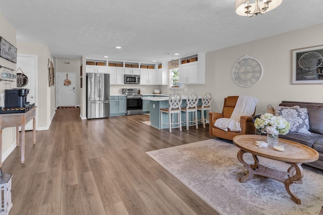 living area featuring a textured ceiling, baseboards, wood finished floors, and recessed lighting