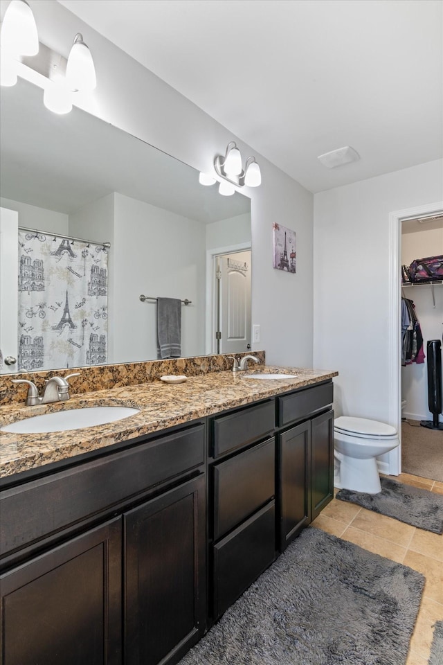 bathroom featuring double vanity, a sink, toilet, and tile patterned floors