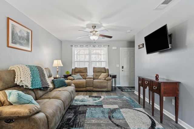 living area featuring baseboards, ceiling fan, visible vents, and wood finished floors