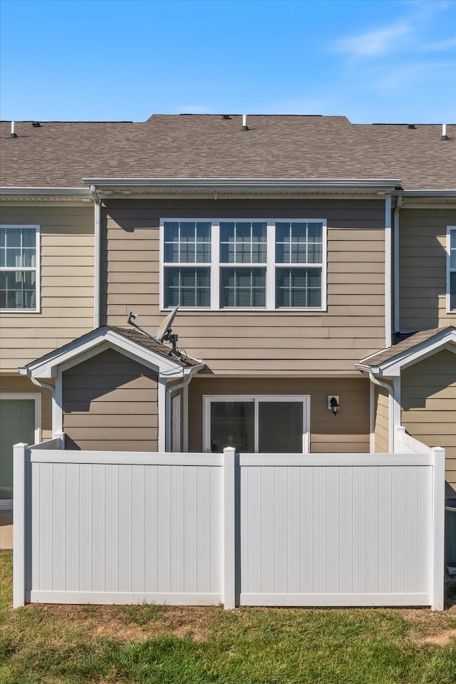 view of home's exterior featuring a shingled roof and fence