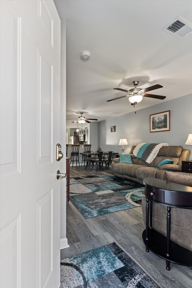 living room with wood finished floors, visible vents, and a ceiling fan