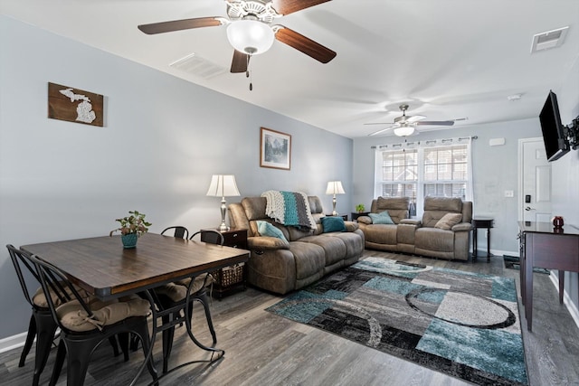 living area featuring visible vents, baseboards, and wood finished floors