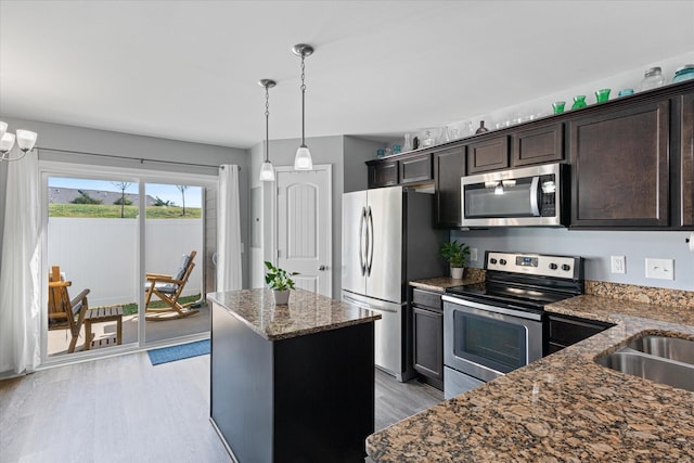 kitchen featuring dark brown cabinetry, appliances with stainless steel finishes, dark stone counters, and light wood finished floors