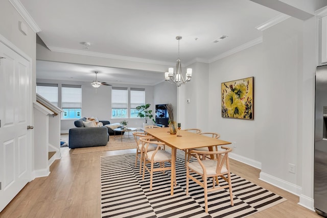 dining room featuring light wood finished floors, visible vents, ornamental molding, baseboards, and ceiling fan with notable chandelier