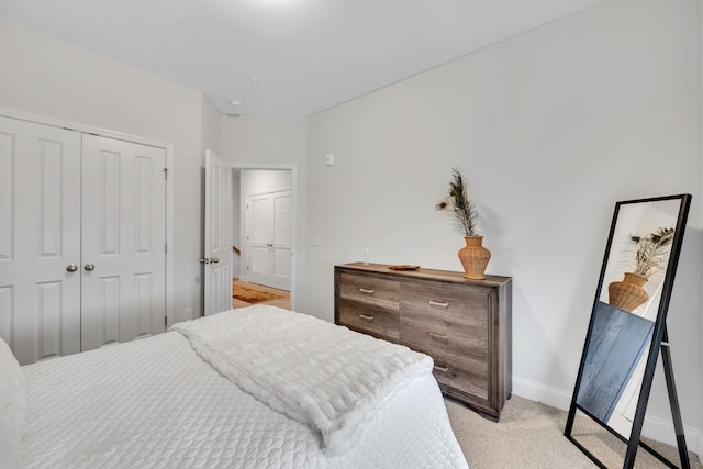 bedroom with baseboards, a closet, and light colored carpet