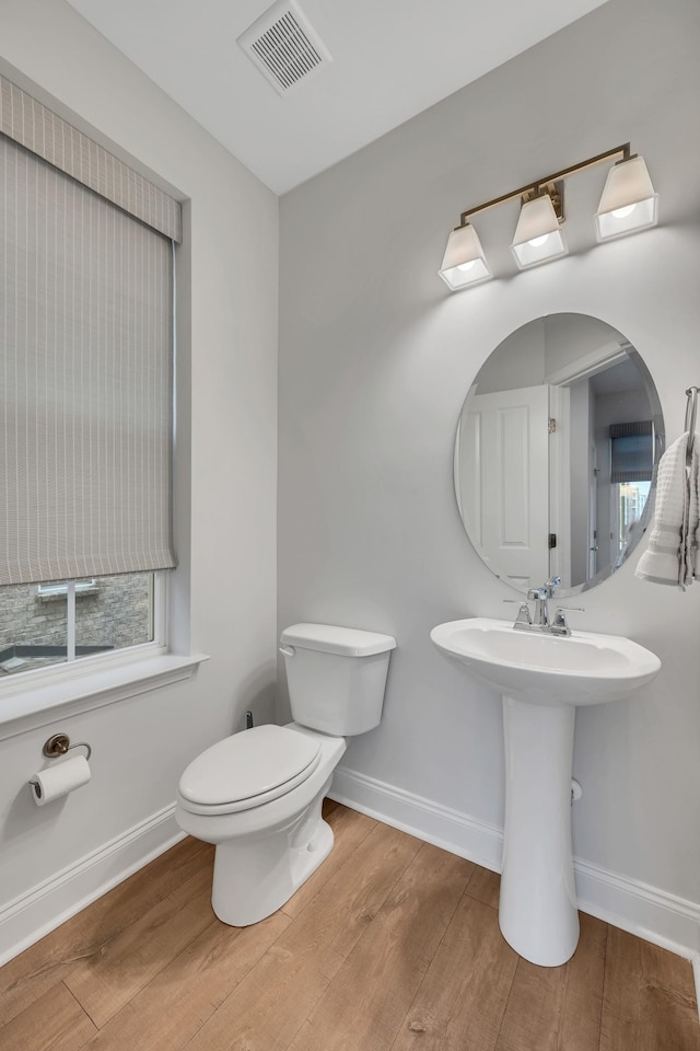 bathroom with toilet, baseboards, visible vents, and wood finished floors