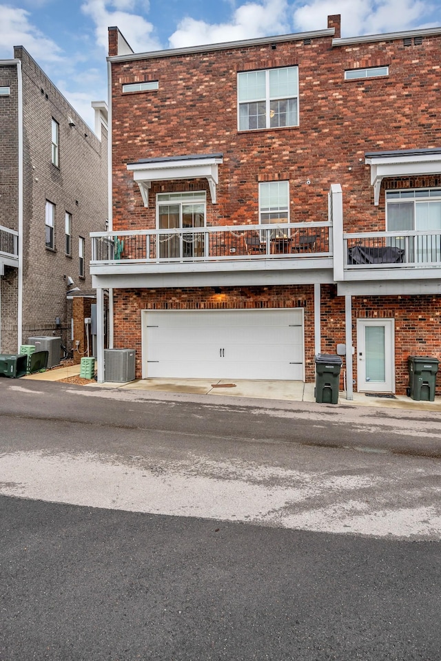 view of front facade featuring a garage, cooling unit, and brick siding