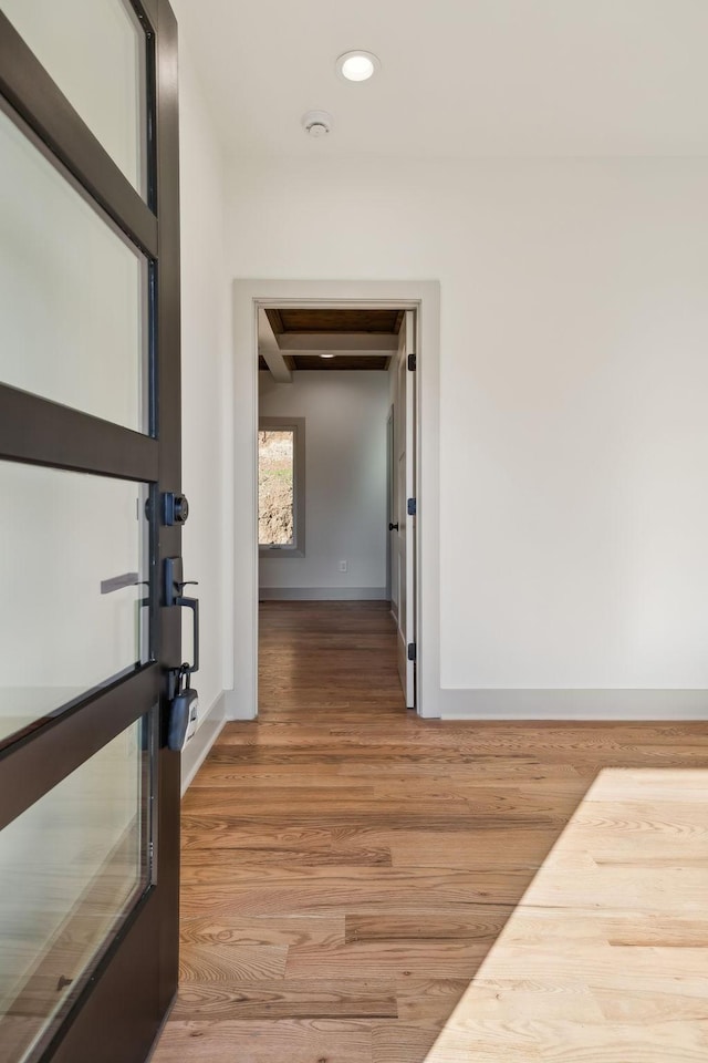 hall featuring light wood finished floors, baseboards, beam ceiling, and recessed lighting