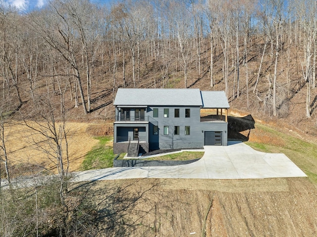 view of front of property featuring concrete driveway and a balcony