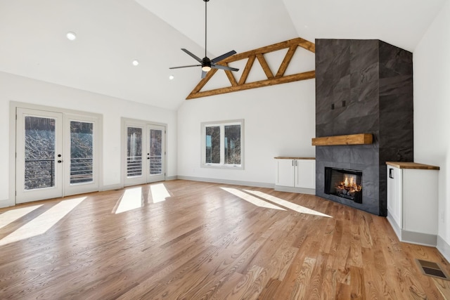 unfurnished living room featuring a tile fireplace, visible vents, baseboards, french doors, and light wood-type flooring