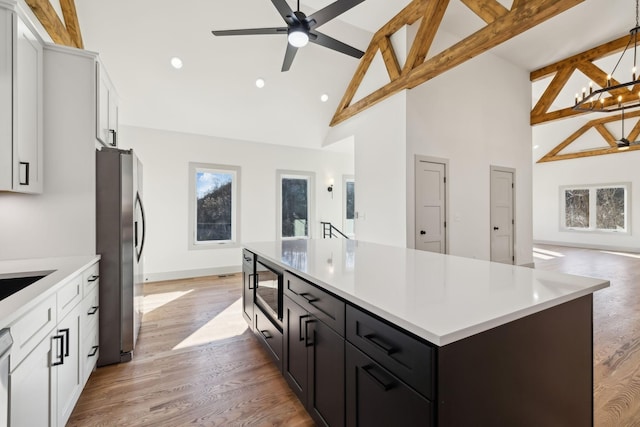 kitchen with light countertops, light wood-style flooring, freestanding refrigerator, and white cabinetry