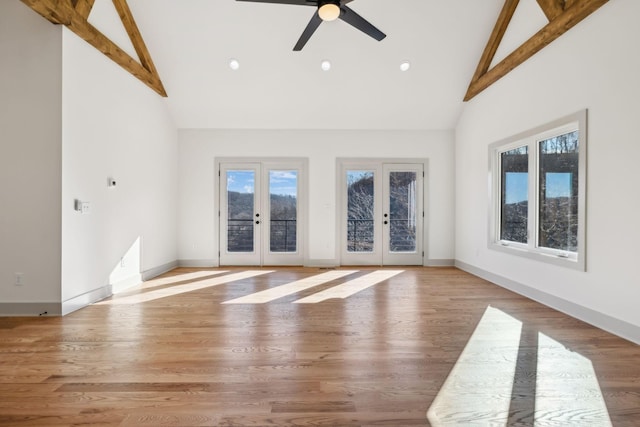 unfurnished living room featuring high vaulted ceiling, french doors, wood finished floors, and beam ceiling