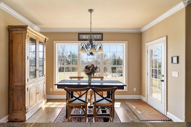 dining area featuring baseboards, an inviting chandelier, light wood-style flooring, and crown molding