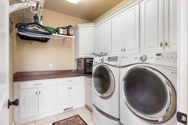 washroom with light tile patterned flooring, cabinet space, visible vents, and separate washer and dryer