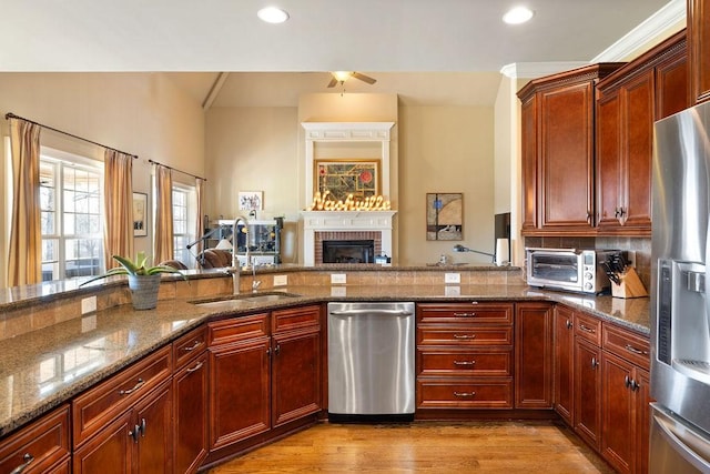 kitchen featuring a toaster, open floor plan, wood finished floors, stainless steel appliances, and a sink