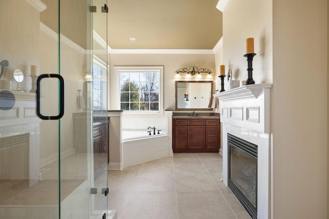 bathroom featuring crown molding, a glass covered fireplace, a shower stall, vanity, and tile patterned flooring