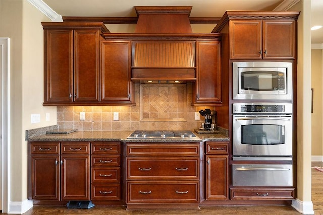 kitchen featuring a warming drawer, stainless steel appliances, dark stone counters, and decorative backsplash