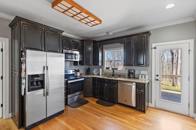 kitchen featuring light wood-type flooring, ornamental molding, stainless steel appliances, and a sink