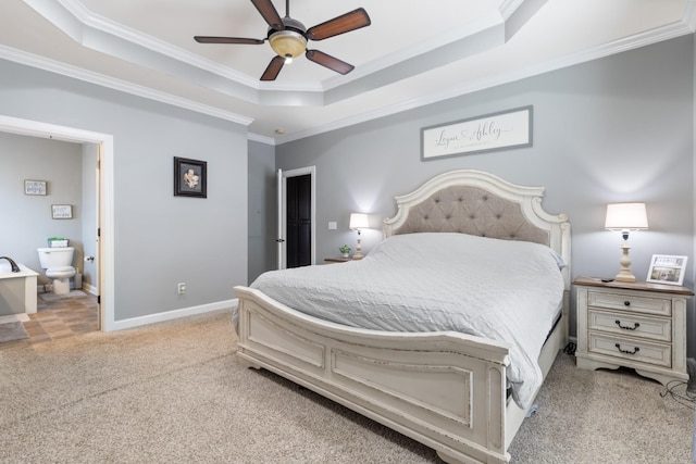 carpeted bedroom featuring ornamental molding, a raised ceiling, baseboards, and ensuite bathroom