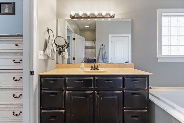 bathroom with a garden tub and vanity